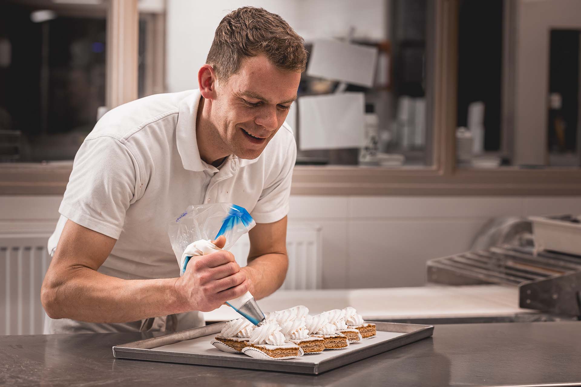 Bakker Ype van der Werf spuit oranjekoek stukjes op